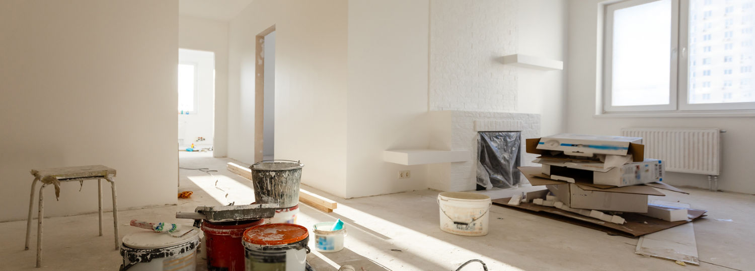 Paint cans and boxes in a bare, white room